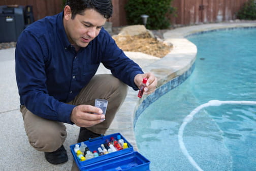 Pool professional testing water chemistry and analyzing pool water clarity
