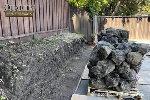 Uneven dirt slope before installation of boulder retaining wall in Northgate/Walnut Acres area, Walnut Creek, CA